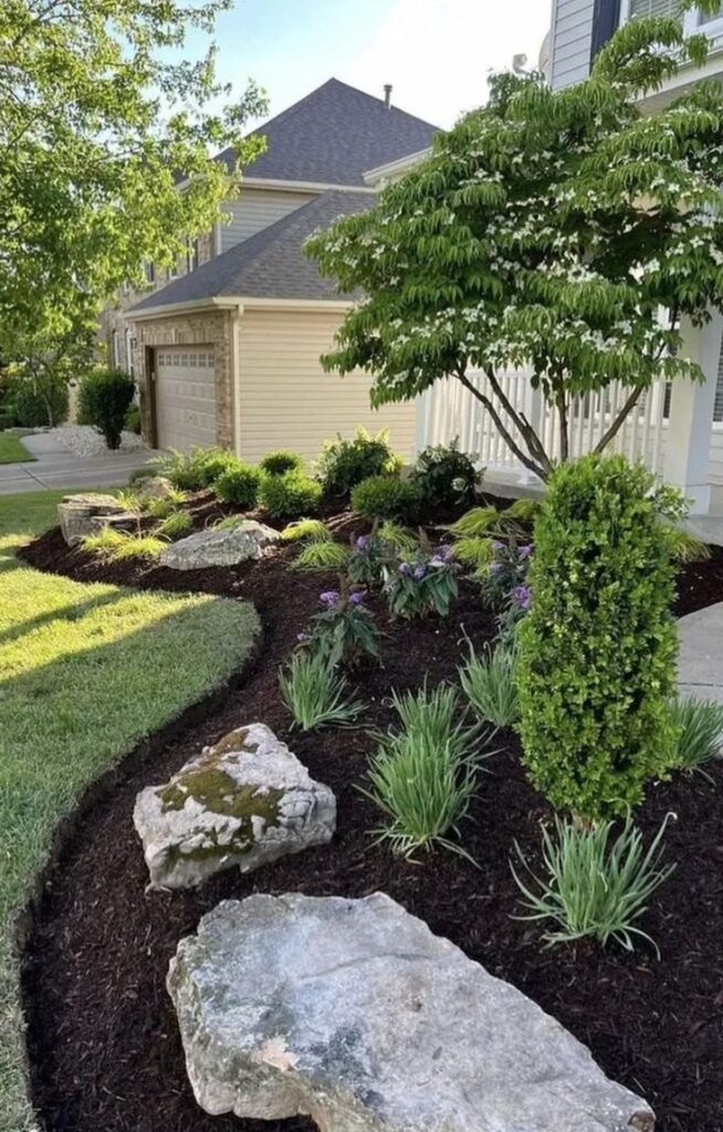 Finished residential landscape bed with mulch, boulders, ornamental grasses, shrubs, and flowers